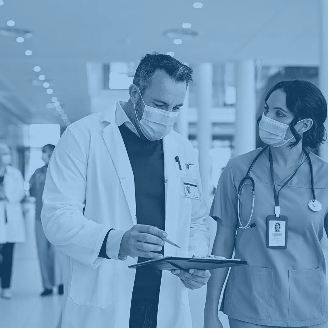 Two healthcare workers discussing documents in a hospital setting.