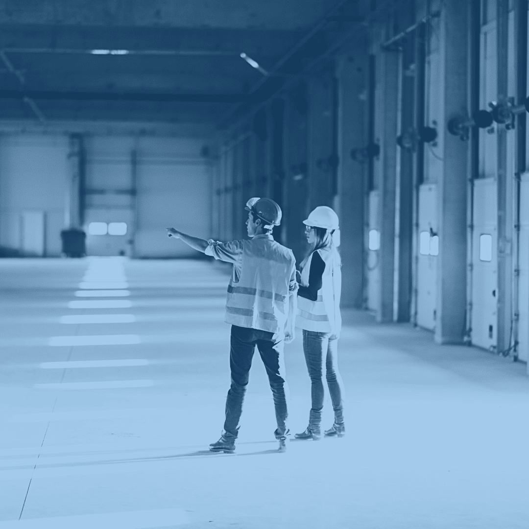 Two facilities managers communicating in a warehouse.